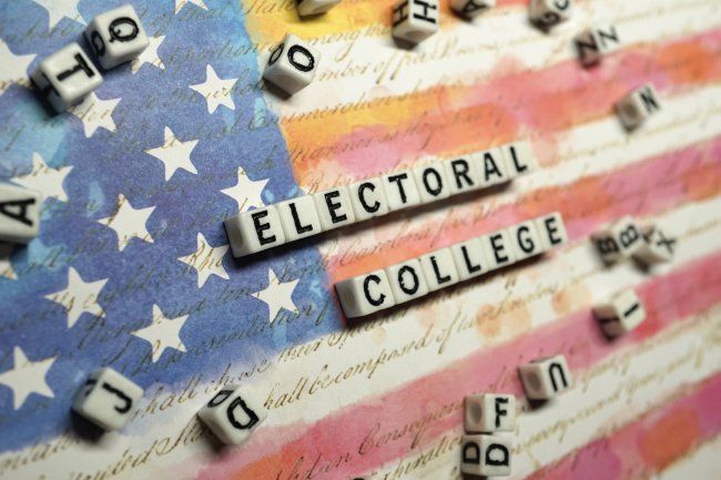 electoral-college-lettered-dice-against-us-flag-istock-1065320490